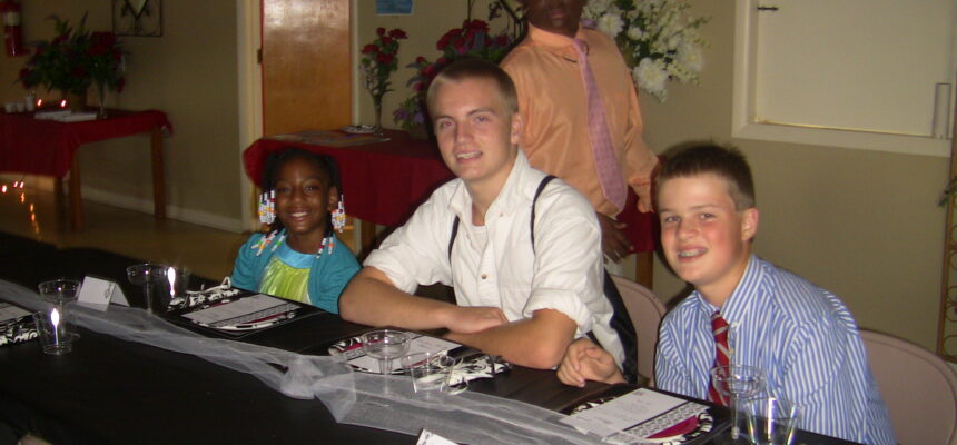 Young individuals from the Durham Youth Alliance dressed in formal attire at the first annual Celebration Dinner in 2013, smiling and engaging with mentors and community leaders. - Courtney Jordan Philanthropy