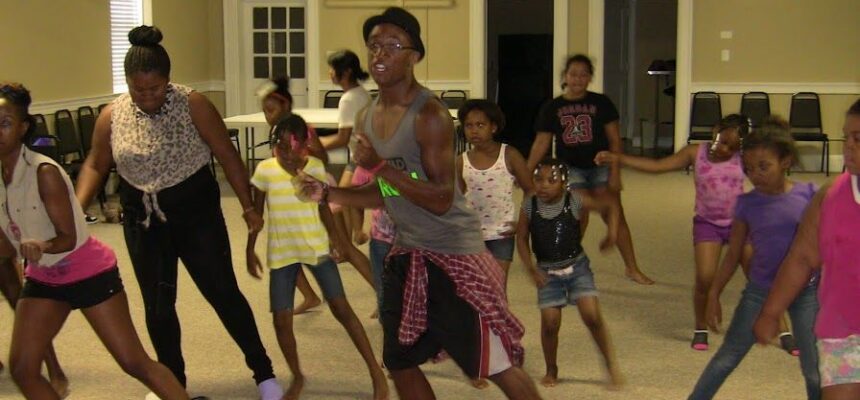 A choreographer leading a dance class at a CJF America Durham Youth Alliance (DYA) event, guiding young participants as they practice movements, fostering creativity and teamwork.