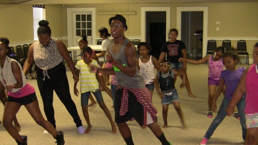 A choreographer leading a dance class at a CJF America Durham Youth Alliance (DYA) event, guiding young participants as they practice movements, fostering creativity and teamwork.